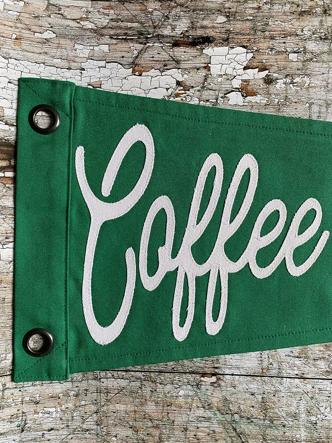 A close up of the word coffee written in ivory canvas as part of a Coffee before Gin pennant flag