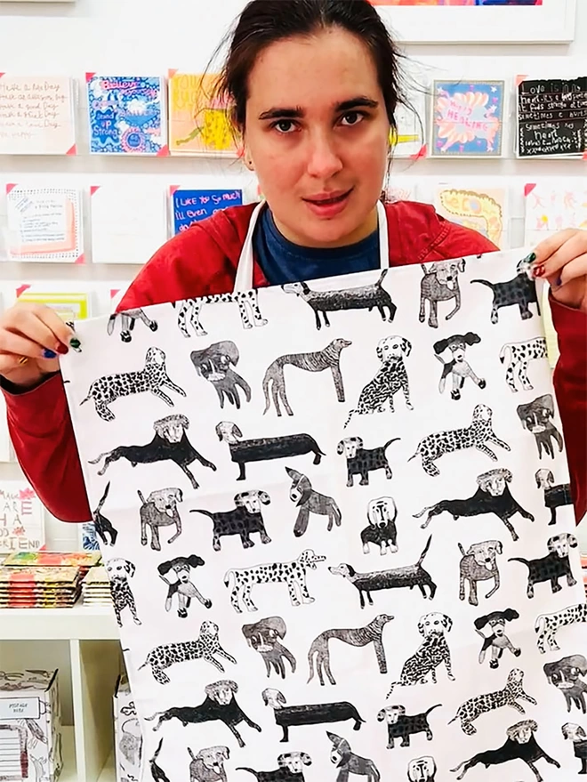 Happy artist holding dogalicious 100% organic cotton charity tea towel with black dog illustrations