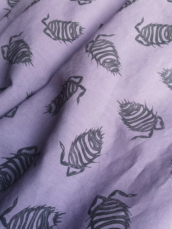 Cotton linen t shirt dress in a soft purple colour with a charcoal woodlouse print. Popper opening centre back and side seam pockets.