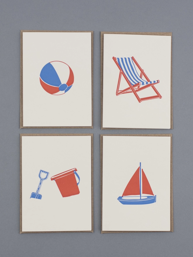 Showing the blue, white and orange designs of the beside the sea small cards including beach ball, deck chair, bucket and spade and toy boat