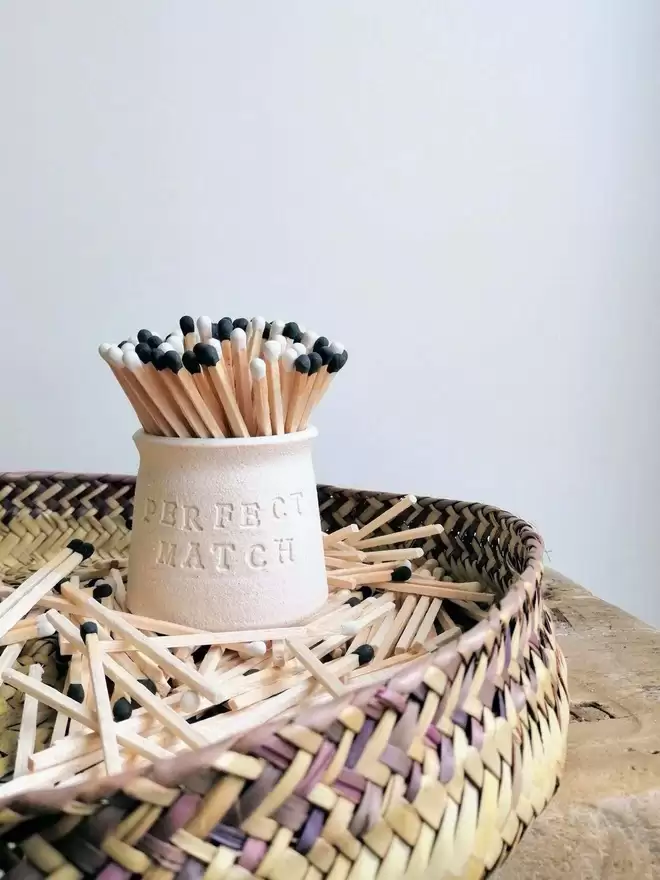 Match pot with perfect match on front sat in a tray of matches. Pot contains black and white matches