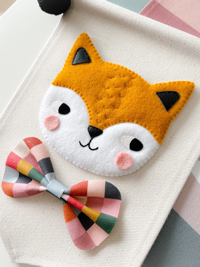 Little hand sewn felt fox on a cream fabric background