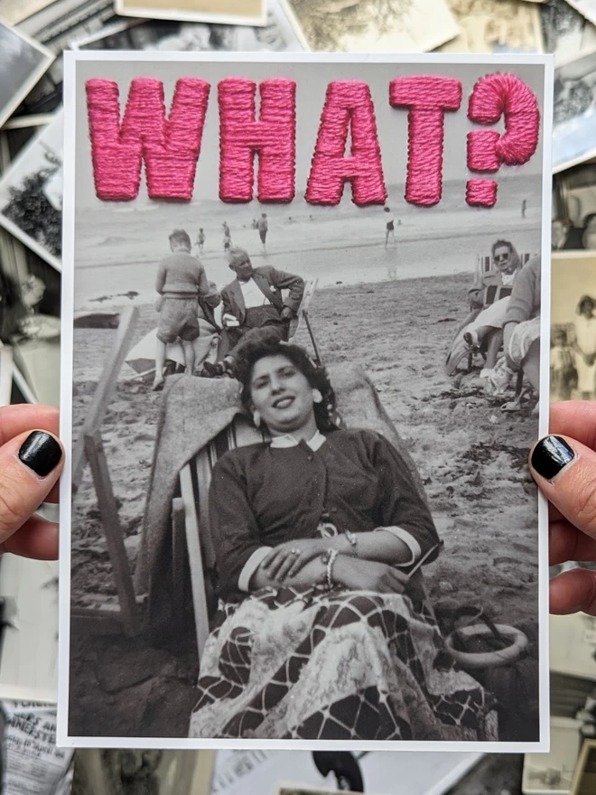  B&W photo print of woman with pink embroidered ‘What?”’ held against vintage photos