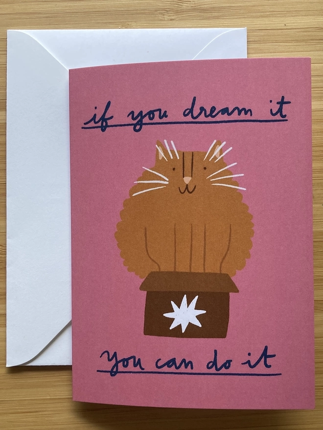 Greetings card with an illustration of a big cat in a small box. The text says 'if you dream it, you can do it'