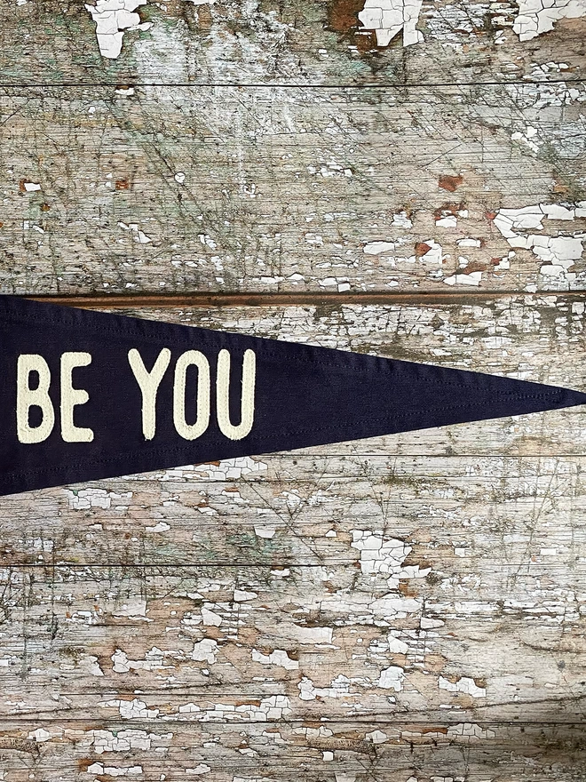 Detail of the navy canvas 'It'll always be you pennant flag. This shows the words 'be you' in ivory canvas.