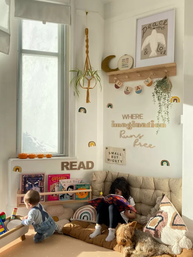 A cosy kids reading corner, filled with kids decor and a large solid wood bookshelf, with a painted bar