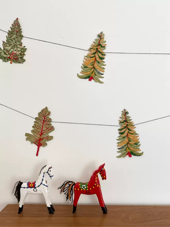 Forest garland on wall with white and red horses in foreground
