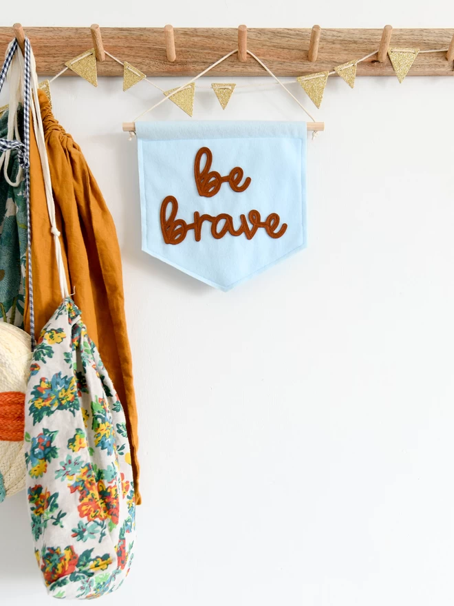 wall banner with be brave written on in cursive font.