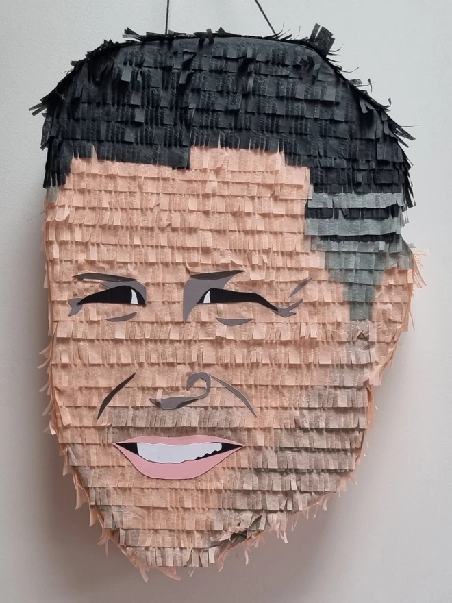 custom made face pinata of a man with stubble squinting to the side