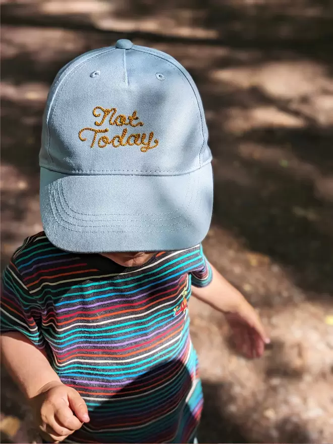 A child wearing a Powder Blue 'Not Today' embroidered hat with Gold thread