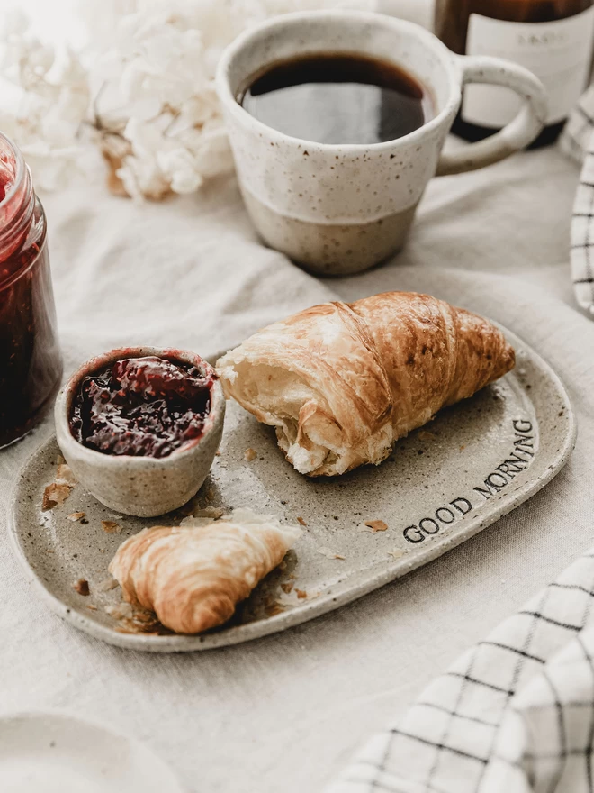 ceramic good morning plate holding a croissant and a pot of jam