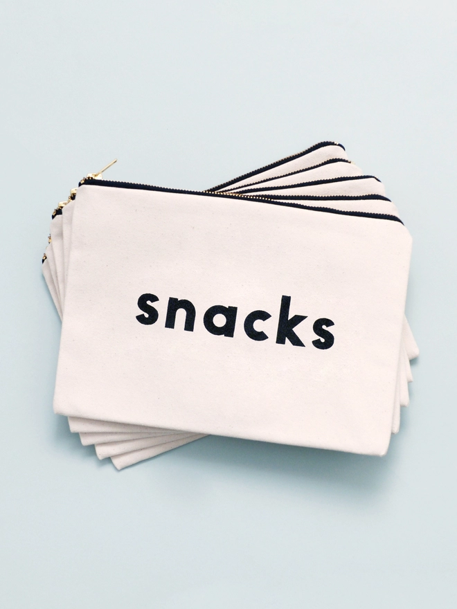 a pile of a natural canvas zip pouches with the words snacks