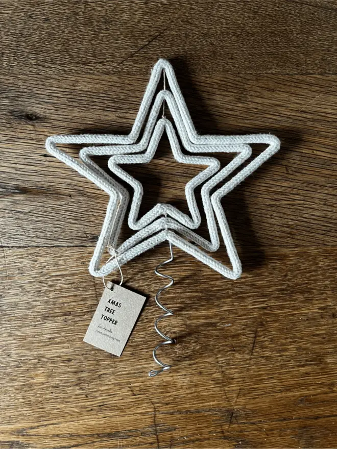 Triple Star Tree Topper made of string and wire resting on an oak table