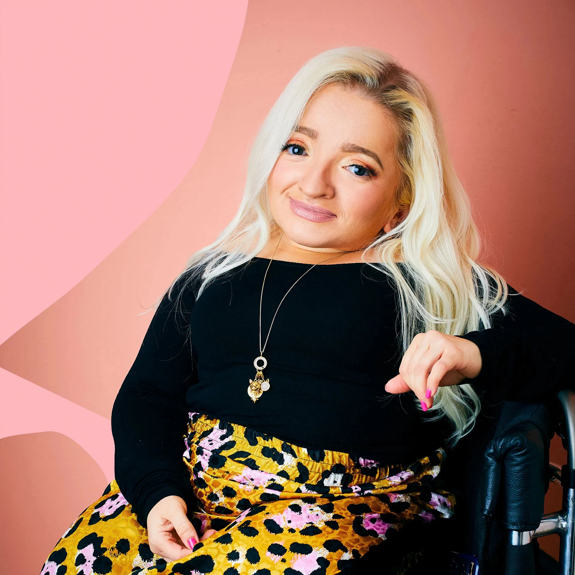 Samantha Renke, actress, presenter & disability activist, smiling at the camera wearing a black top and yellow leopard skirt.