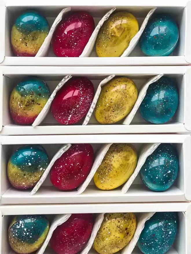 an assortment of coloured easter eggs in a white box
