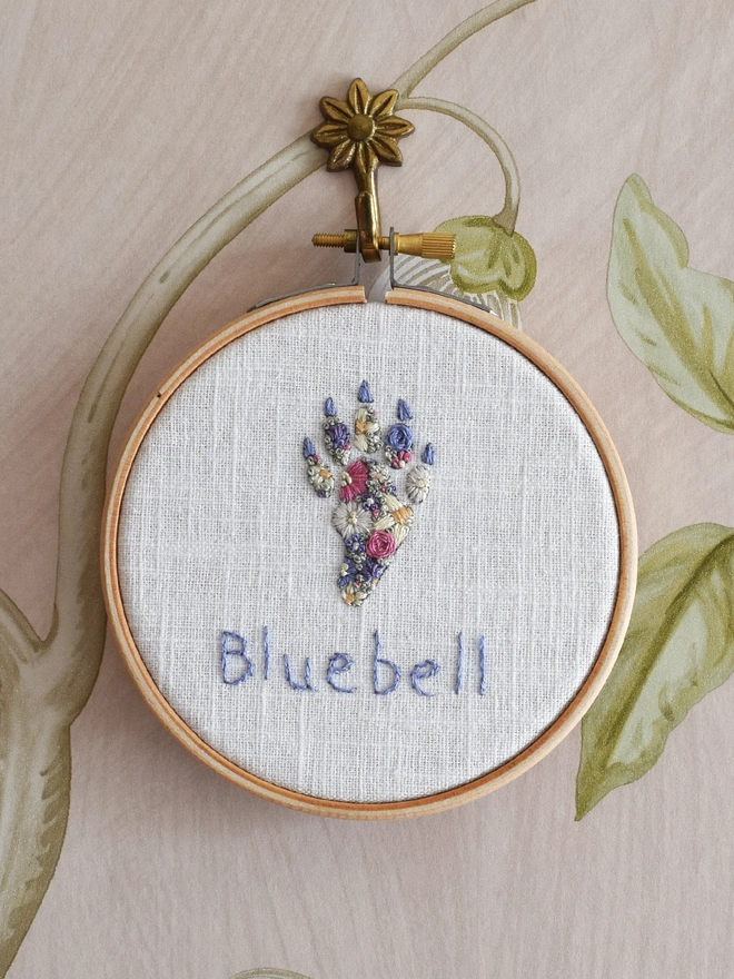 Floral Meadow Cat Paw, of Lavender Blues and Buttermilk yellow blossoms.  Displayed in an embroidery hoop on a wall hook.