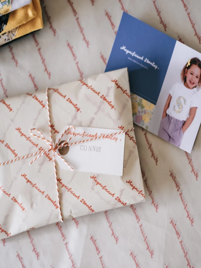 a gift wrapped item in branded tissue and twine with a hand stamped name tag.