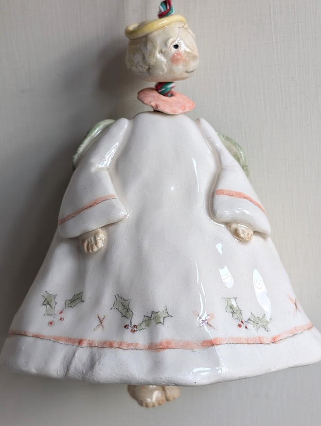 angel bell in pottery with handpainted holly, berries and a bead for the angels head with blonde hair and little ceramic legs for the clanger