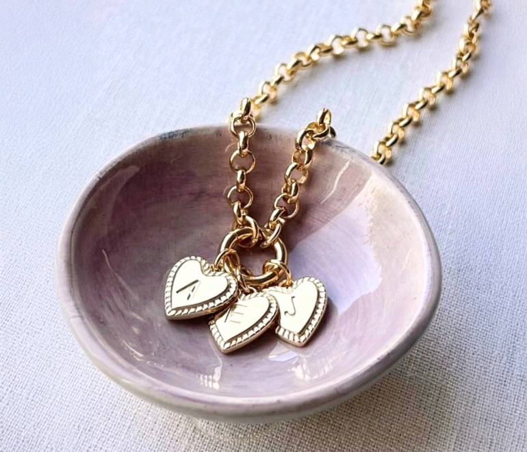 Family initial charm necklace. A charm necklace in gold with three heart shaped charms with initials on them.