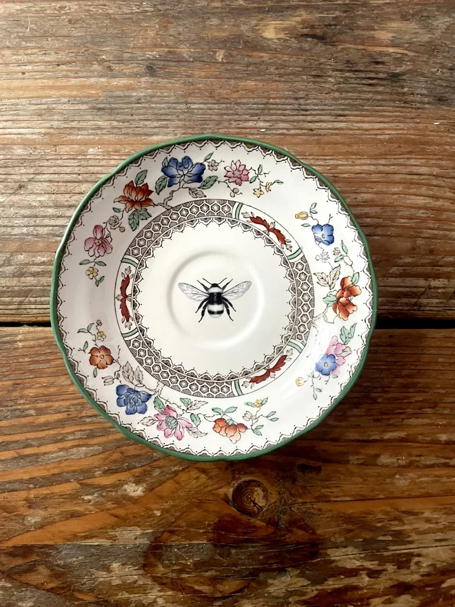vintage plate with an ornate border, with a printed vintage illustration of a bee in the middle 