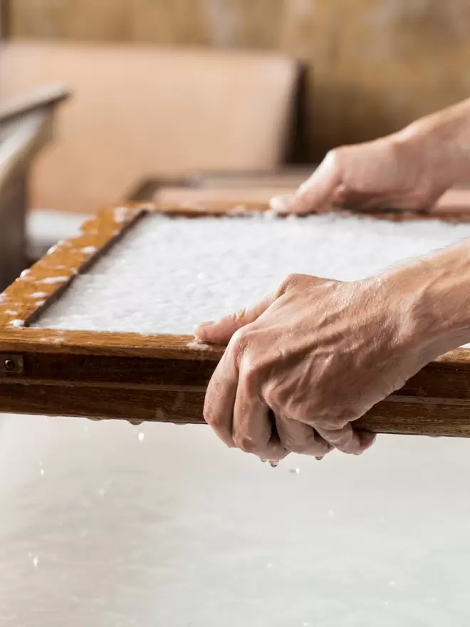 Hands holding a deckle with pulp in showing the handmade paper making process