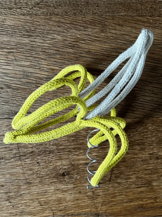 String and wire Xmas tree topper shaped like a peeled banana resting on an oak table