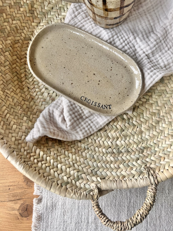 oval croissant plate, laid on a tea towel in a woven basket