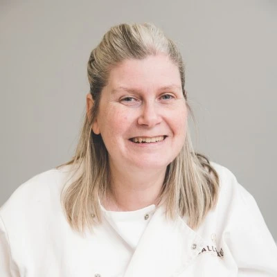 Amanda smiling at the camera in white chef's coat