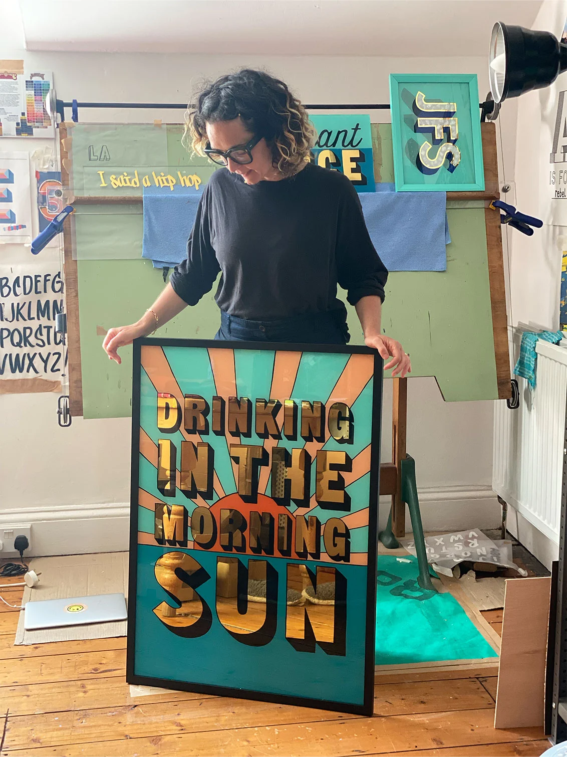 amy in the studio surrounded by paintings including drinking in the morning sun