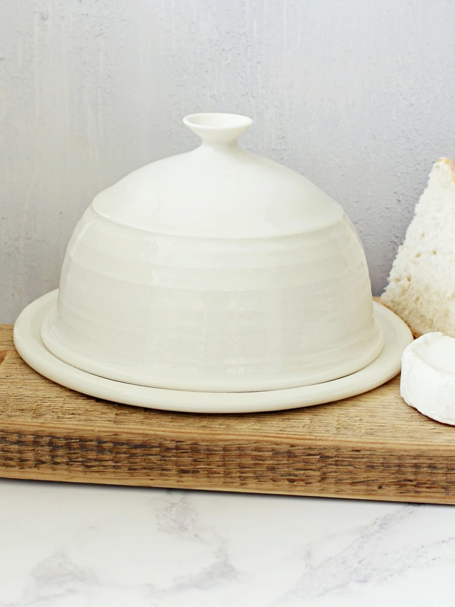 satin cream domed butter dish on chopping board with bread and goats cheese