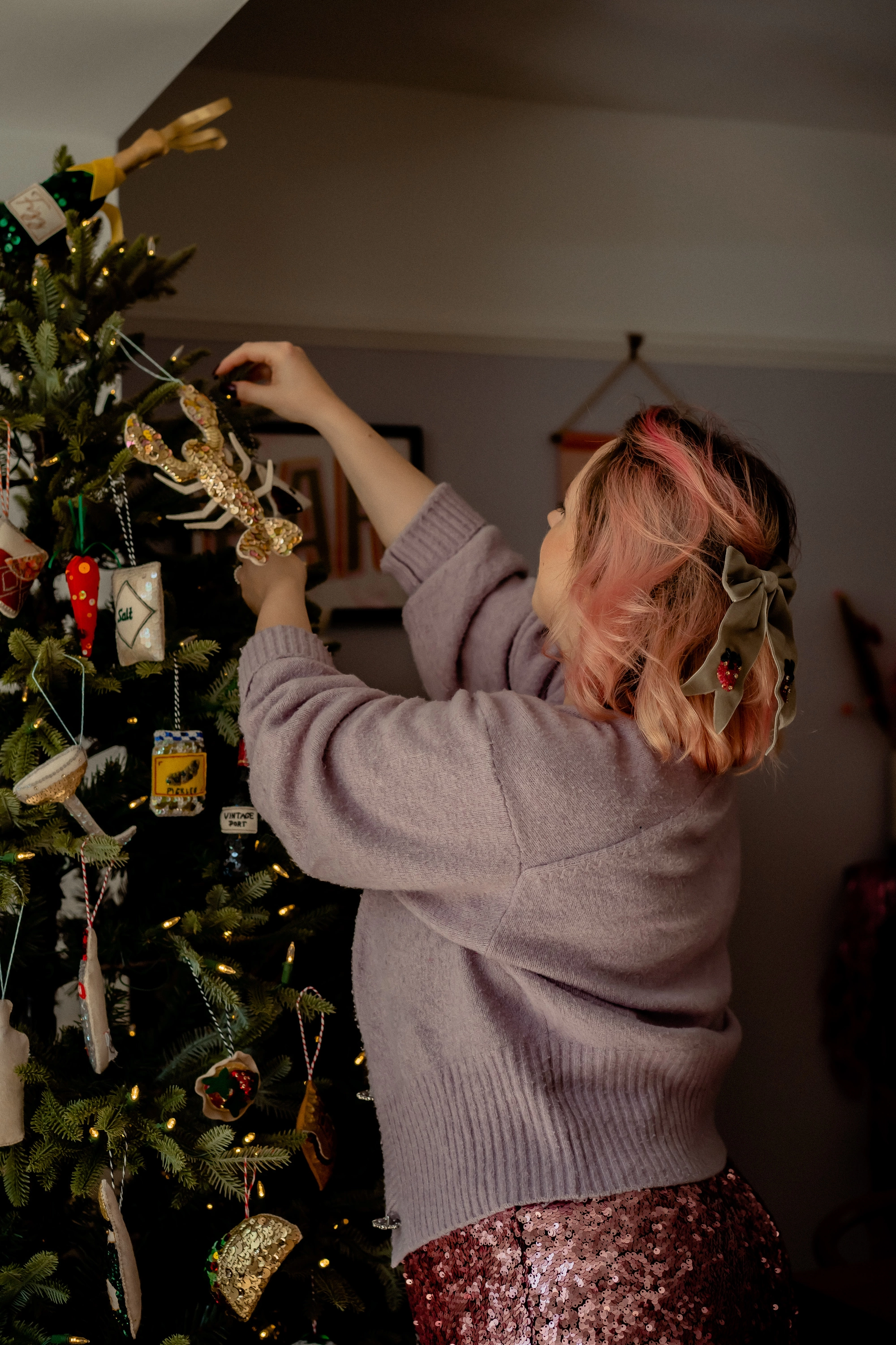 Kate stands decorating her tree, holding a golden sequinned lobster