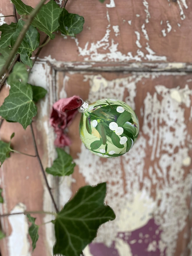 Hand painted mistletoe ceramic bauble pale green background 