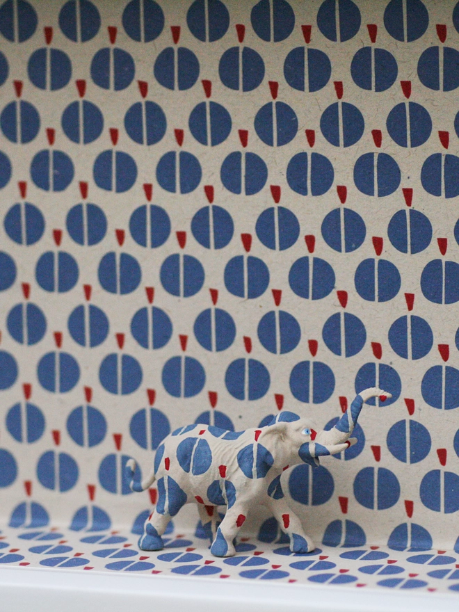 Miniature elephant blending seamlessly into a beautifully wallpapered wall