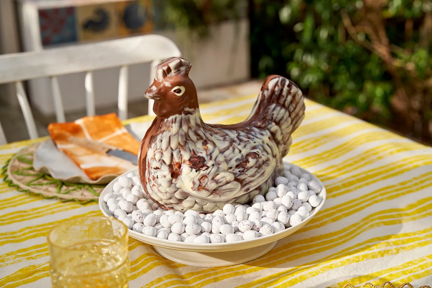 Giant chocolate Easter hen. A giant chocolate hen on a bed of mini eggs on a yellow tablecloth