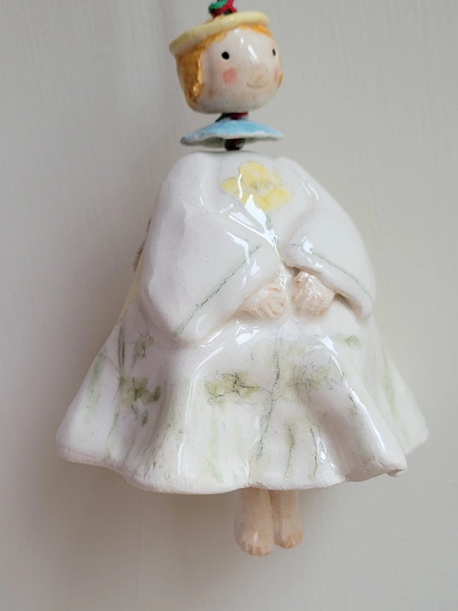 angel bell in pottery with handpainted buttercup flowers and a bead for the angels head with ginger red hair and liitle ceramic legs for the clanger