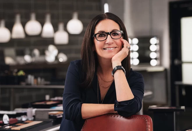 Bobbi Brown, founder of Bobbi Brown and Jones Road Beauty, smiling at the camera, wearing a navy blue blouse.