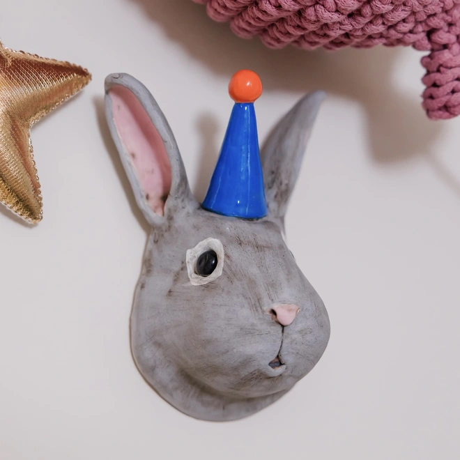 Rabbit bunny head ceramic sculpture with a party hat in a Kids room