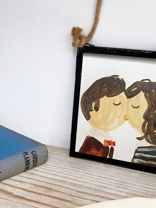 framed portrait of two people kissing