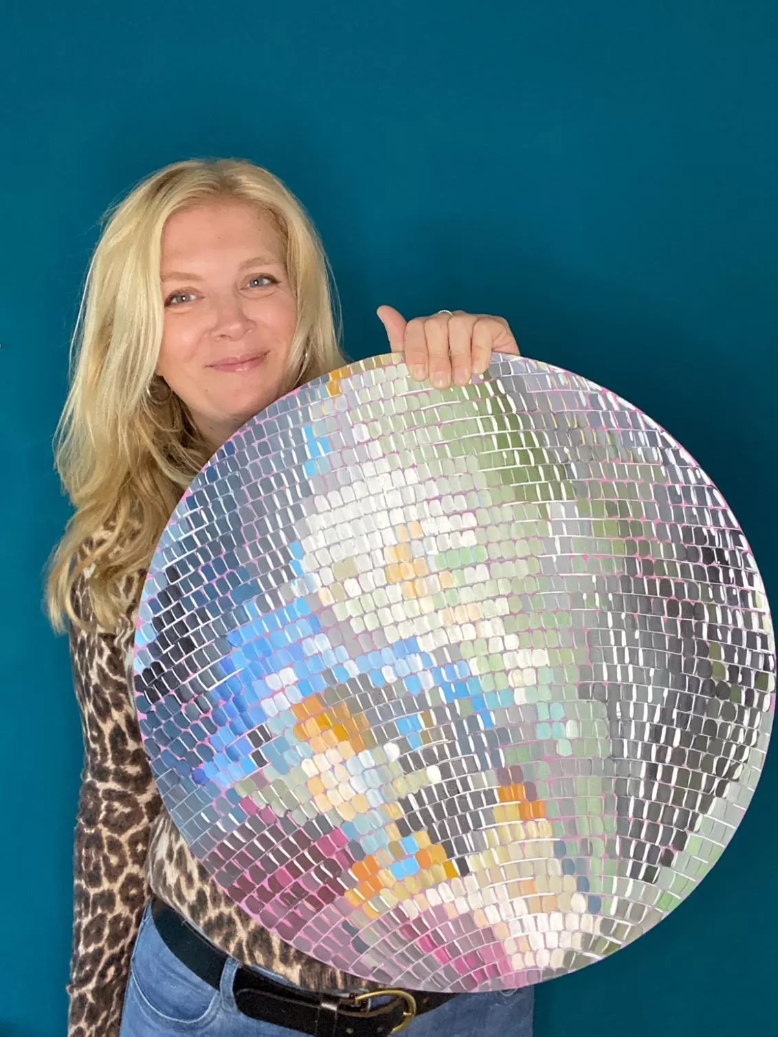 a person holding a large round disco ball painting 