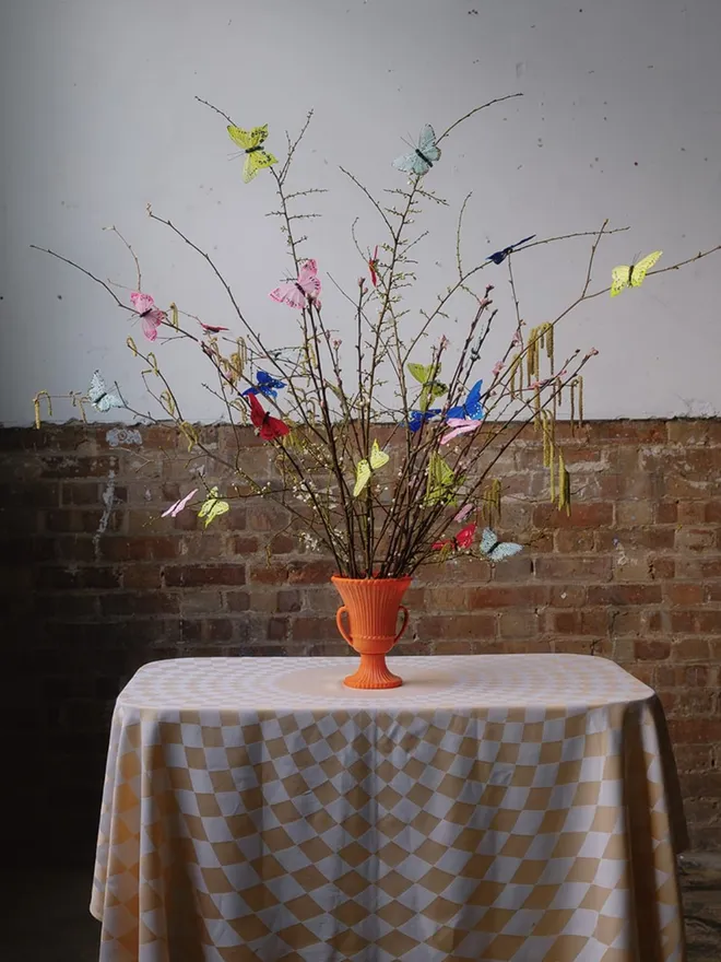 Butterfly clip on decorations adorning blossom branches in a vintage urn