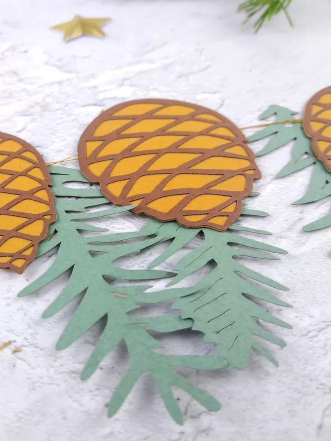 Closeup of Pinecone Paper Garland mixed with blue green spruce paper garland