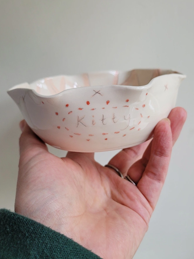 pink and red kitty cat bowl with fluted rim held in a hand