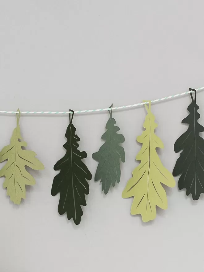 Section of Green Oak Leaf Garland showing 5 paper oak leaves in 3 different shades of green