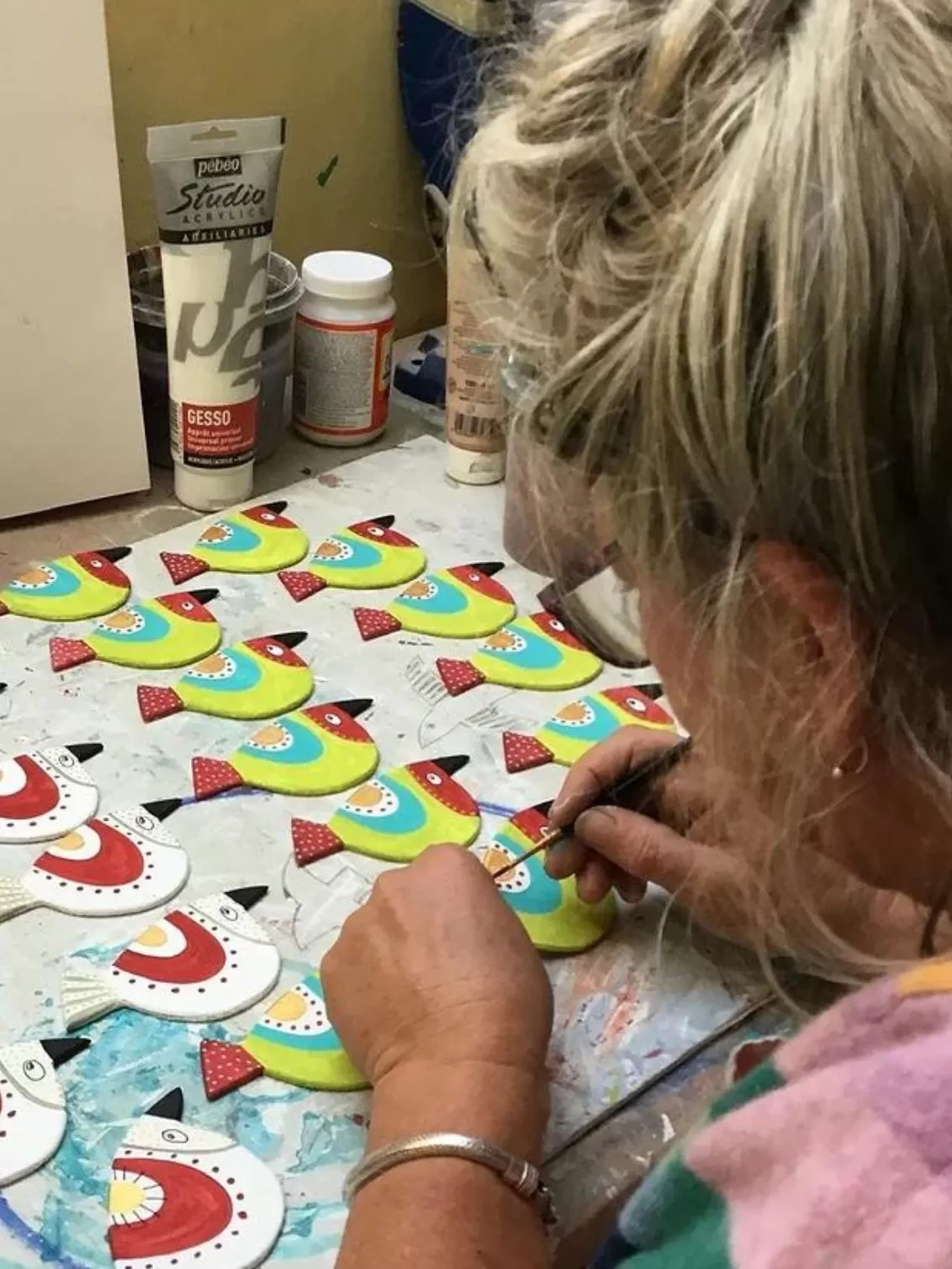 Philippa hand painting her bird products in her studio - over the shoulder shot