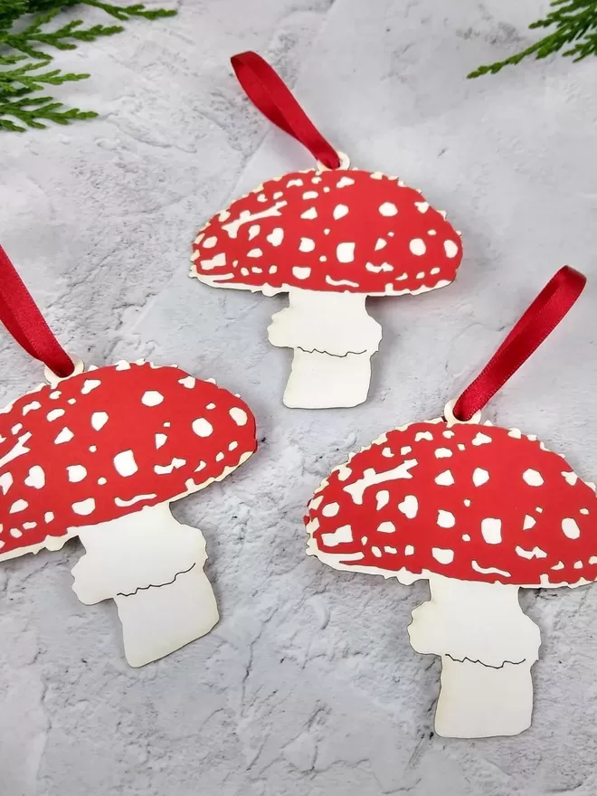 3 bright red and white paper mushroom ornaments with bright red ribbon hanging loops