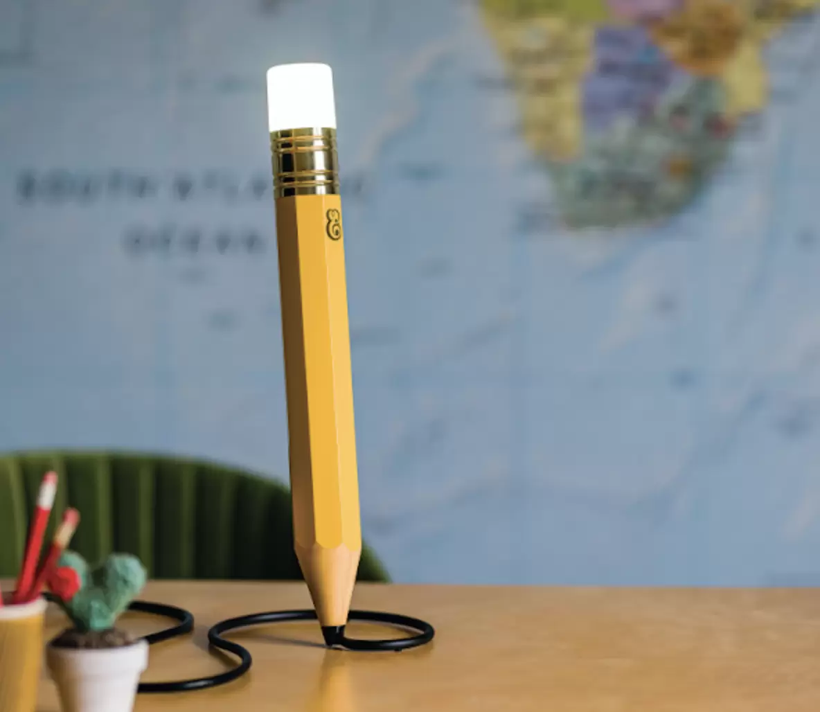 Pencil light seen on a desk with a map wallpaper behind.
