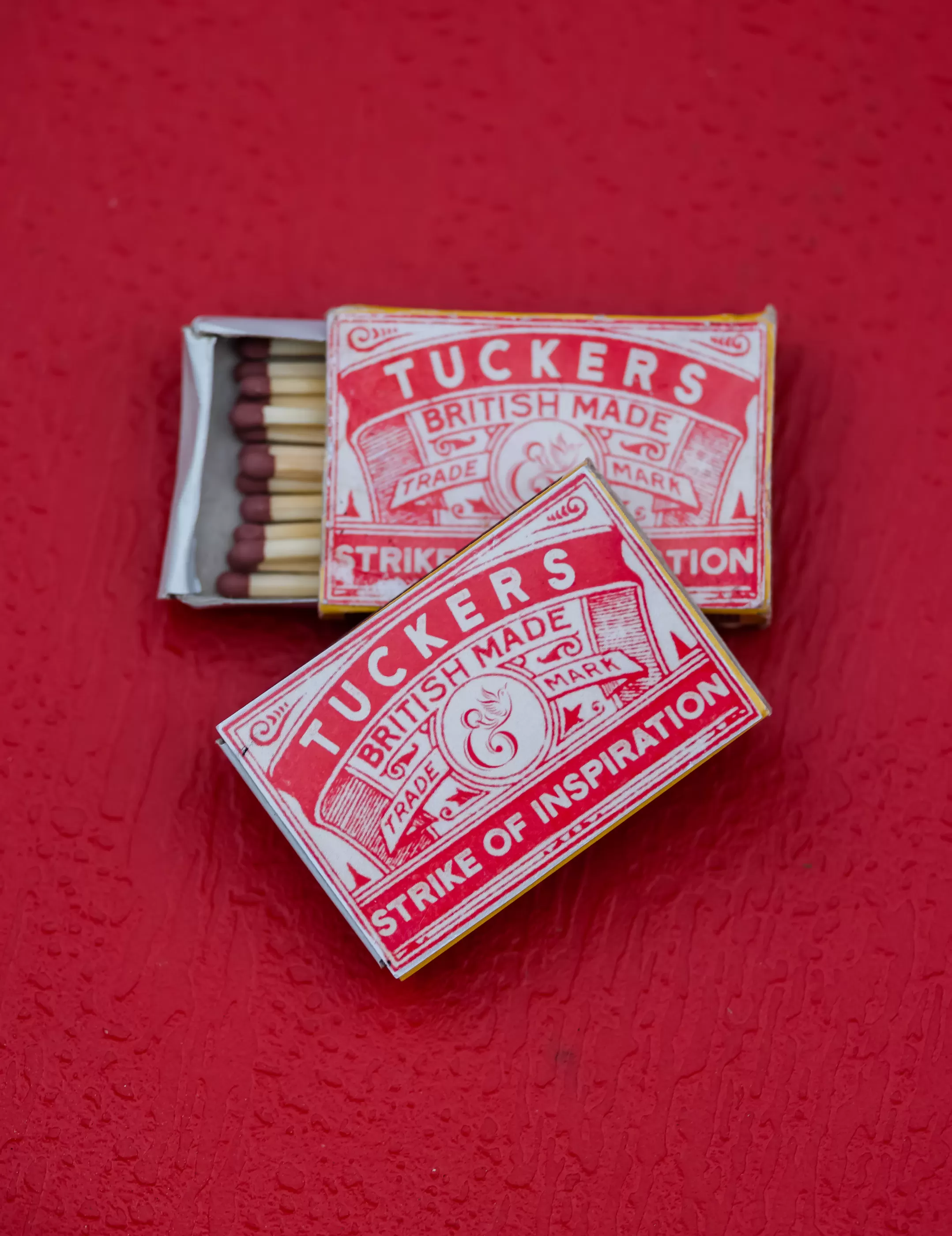 Two boxes of matches called Tuckers Strike of Inspiration on a red background