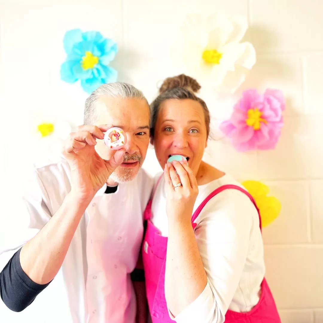 Founders Vincent and Callie The March Hare Bakery holding colourful macarons with flowers in the background