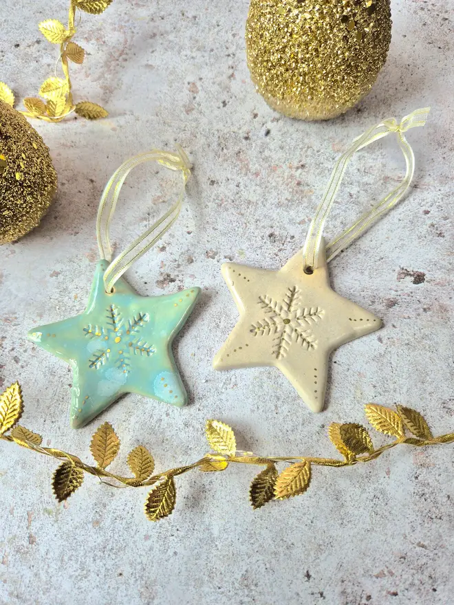 Star Christmas decorations, ceramic decorations, dream catcher, christmas star, pottery, Jenny Hopps Pottery, J.H Pottery, J.Hopps Pottery, Clay star, gift, christmas tree, blue with white and cream with gold details, on a light gold ribbon, photographed on a branch with Christmas lights