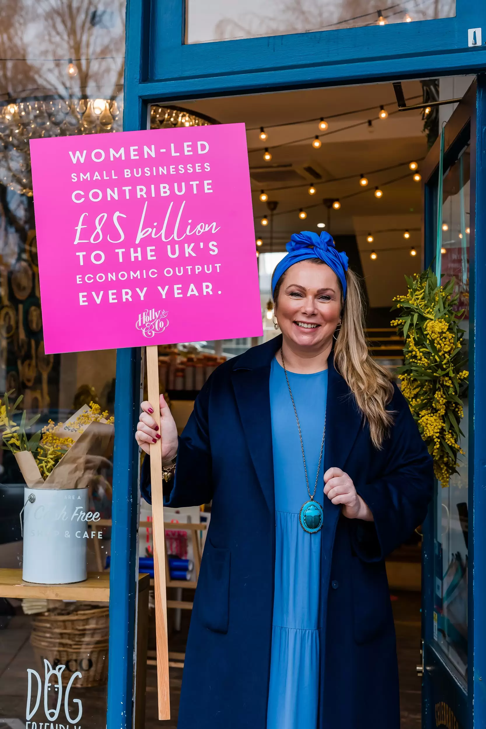 Women led small businesses contribute £85 billion placard held by Holly Tucker MBE in front of the Holly & Co Workshop 